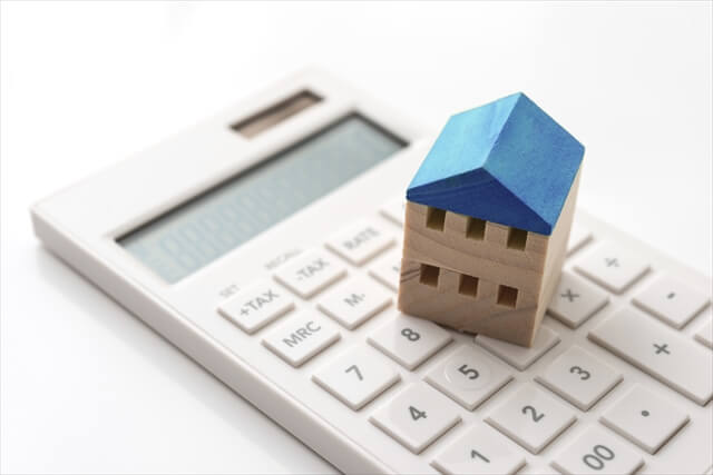 家の模型と電卓（賃貸契約にかかる初期費用を計算する様子）